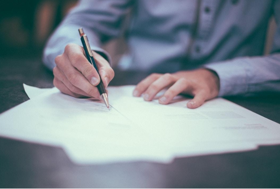 Businessman sitting at a desk writing on a piece of paper that shows a node diagram