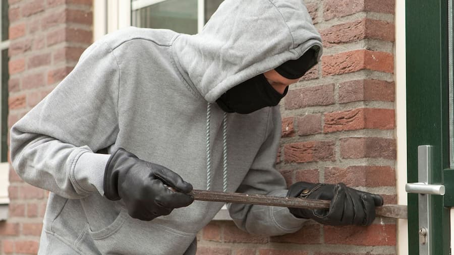 A thief trying to enter a shop showcasing the importance of security systems to enhance workplace safety